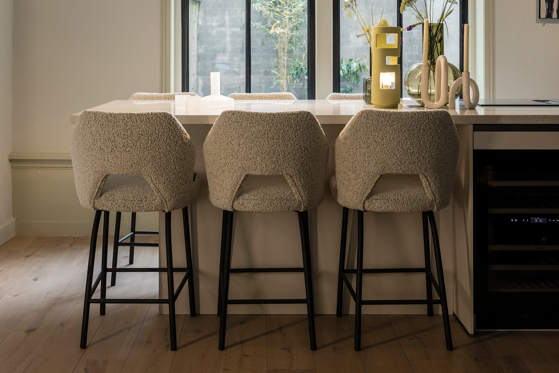 Wit kookeiland met beige barstoelen