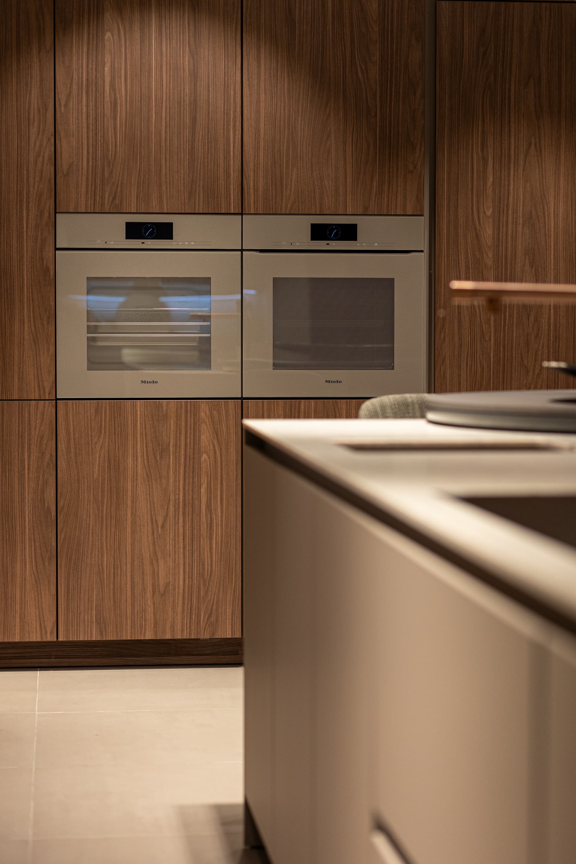Donker houten hoge keukenkasten met twee beige ovens naast elkaar