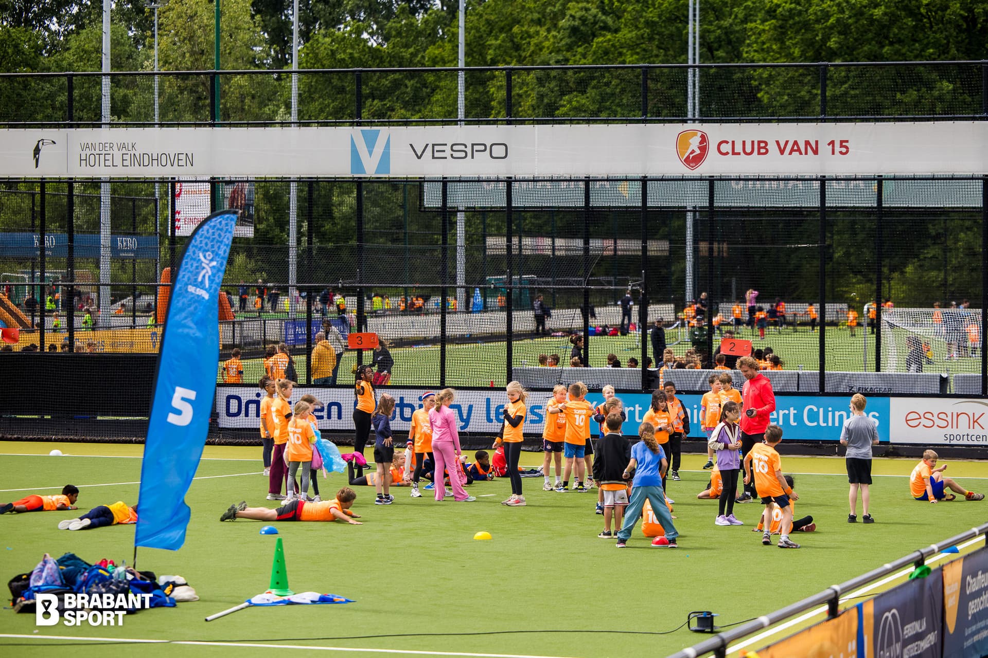 Foto voetbalveld waar je in de verte kinderen met oranje shirts ziet spelen