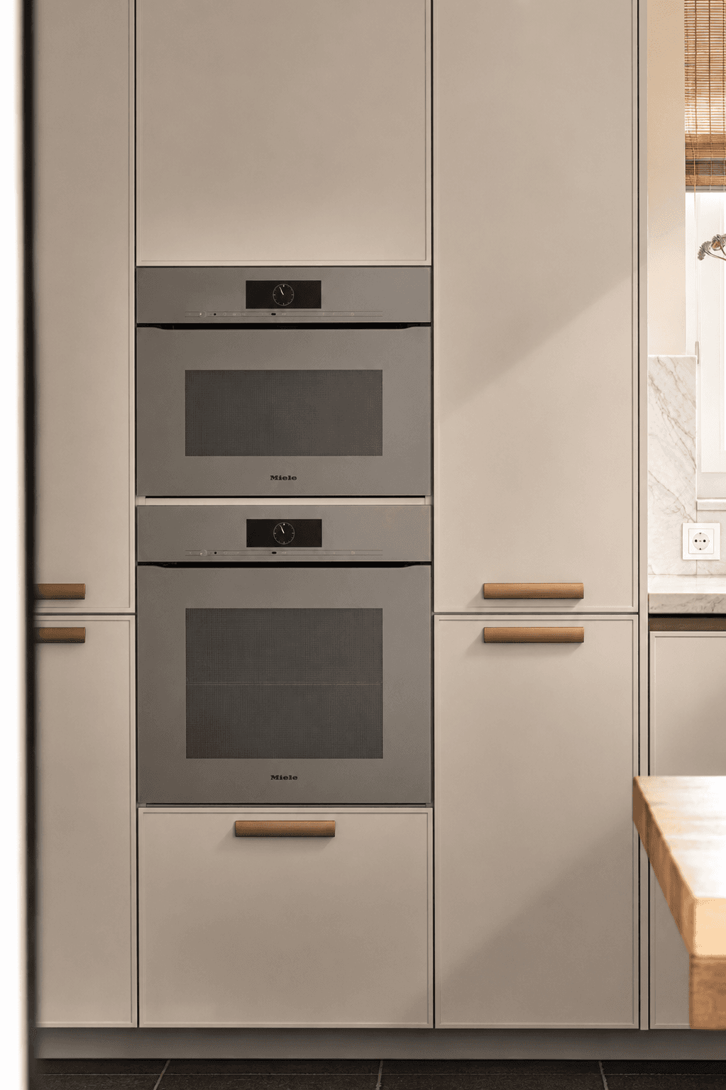 Keuken met hoge kasten houte grepen en twee zilveren ovens