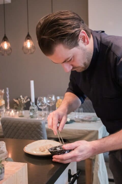 win-private-dining-1.jpeg Kok die met pincet eten vanuit bakje op bord plaatst