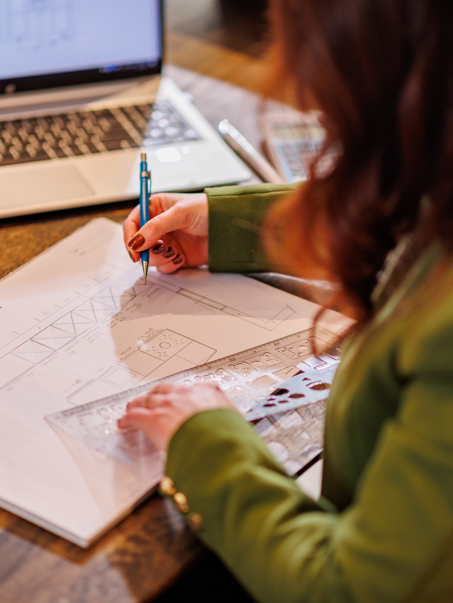 Foto van vrouw waar je over de schouder meekijkt naar hoe zij een werktekening van een keuken maakt